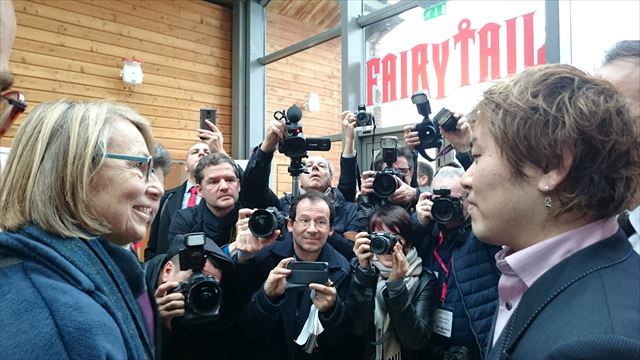 報道陣に囲まれる中、フランソワーズ・ニセン文化相(左)をエスコートする真島ヒロ氏(右)